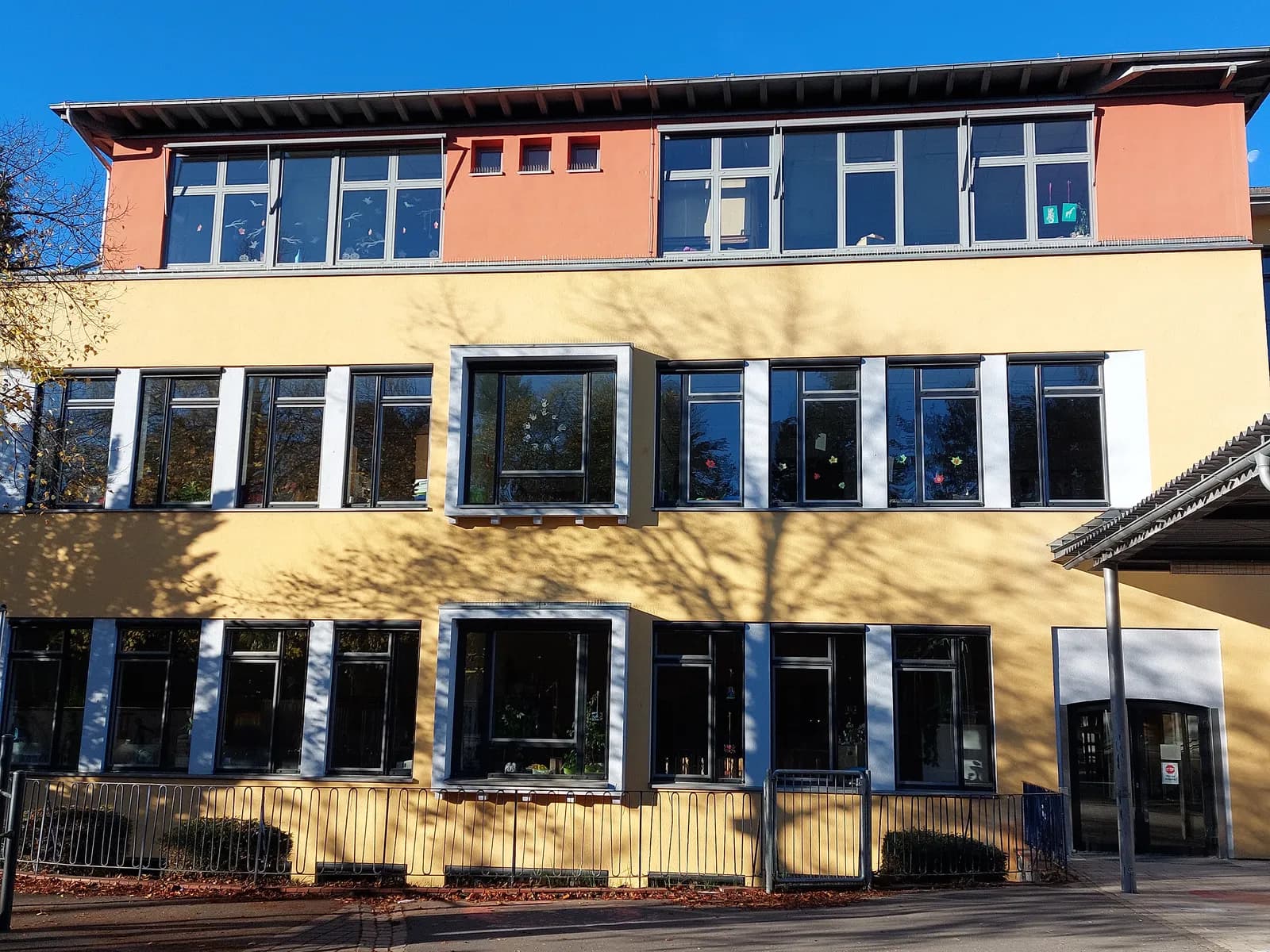 Fassade des Hauptgebäudes der Regenbogenschule mit großen Fenstern